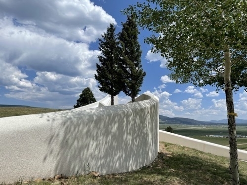 White amphitheater walls with trees and grassy areas at Vietnam Veterans Memorial in Cimarron New Mexico