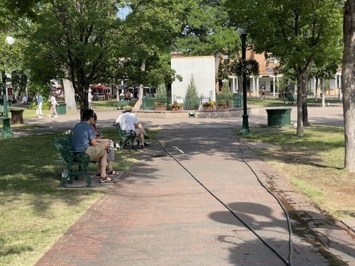 People sitting on bench near center of Santa Fe Plaza in Santa Fe New Mexico