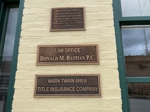 Placard for National Register of Historic Places on side of building and sign for Mark Twain Area Title Insurance Company in downtown Hannibal Missouri